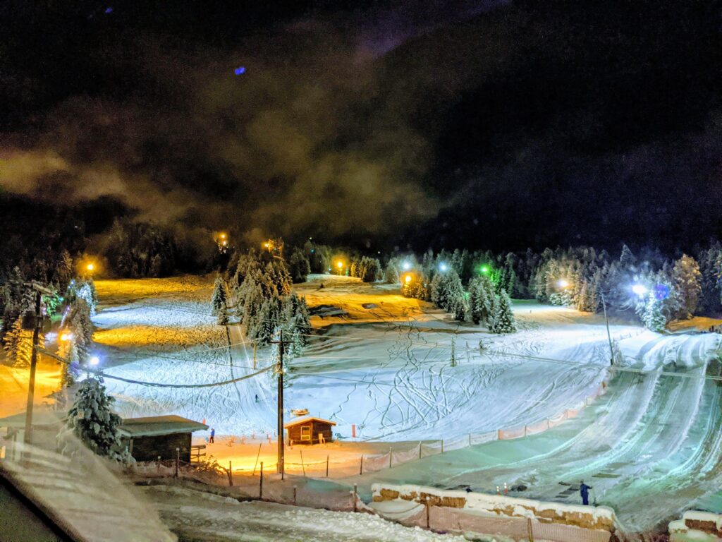 Image of harper Mountain ski hill covered in snow at night, with multiple coloured lights illuminating the hill.