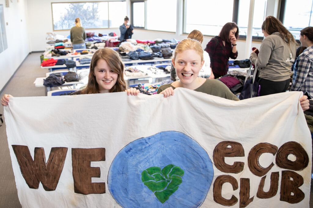Two students hold up a banner that says "we heart eco club".