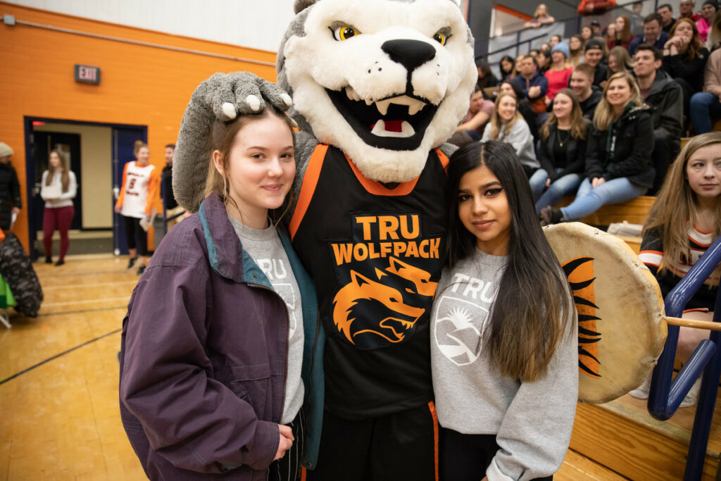 Two girls pose next to wolfpack mascot Wolfie.