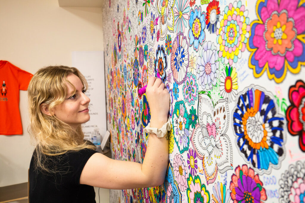 A student colours in flowers on the colouring wall in the Wellness centre.